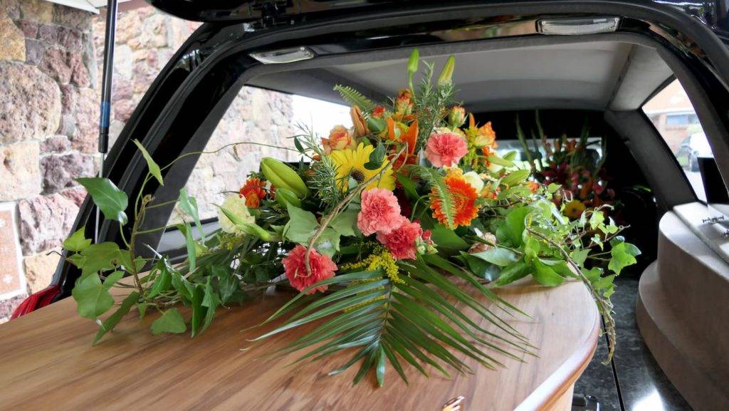 Flowers on top of coffin in back of hearse