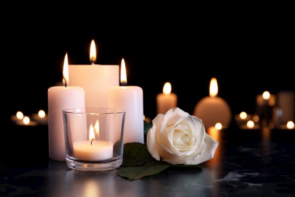 White candles and rose on black marble surface